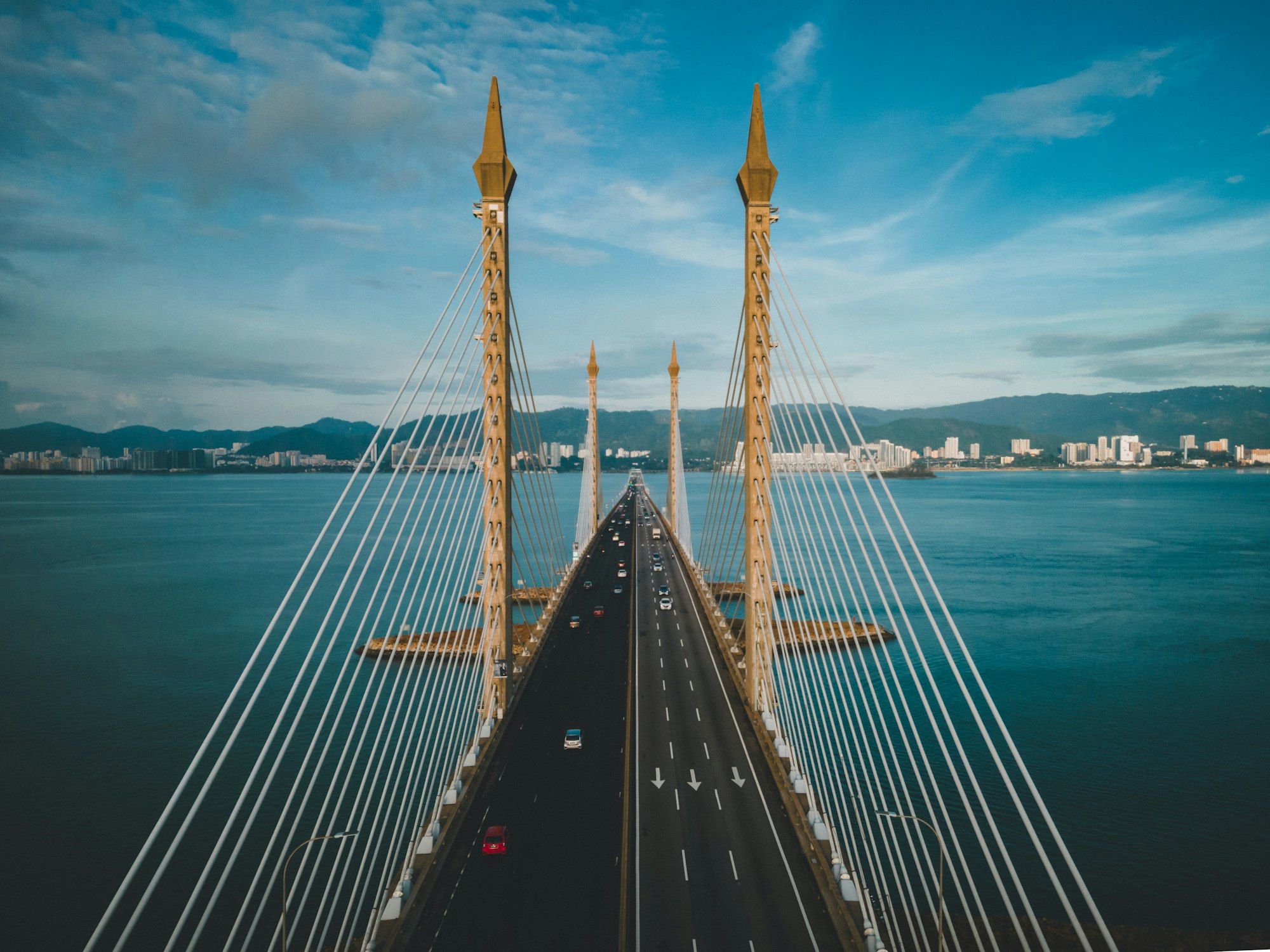 Aerial shot of the Penang Bridge in Malaysia crossing Penang Strait with a city in the background