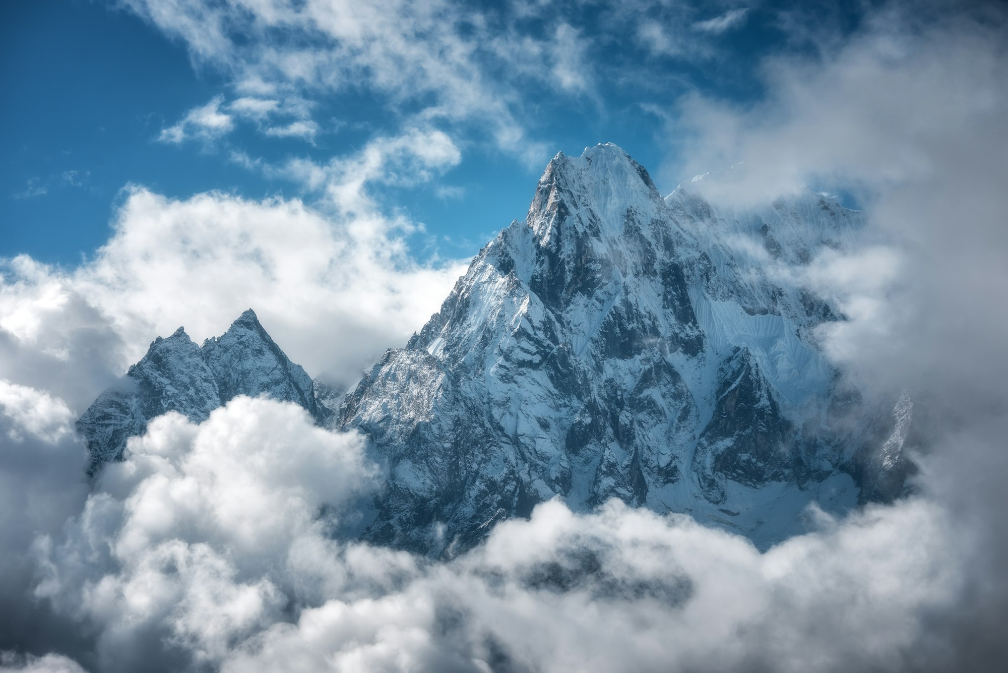 Manaslu mountain with snowy peak in clouds in sunny bright day