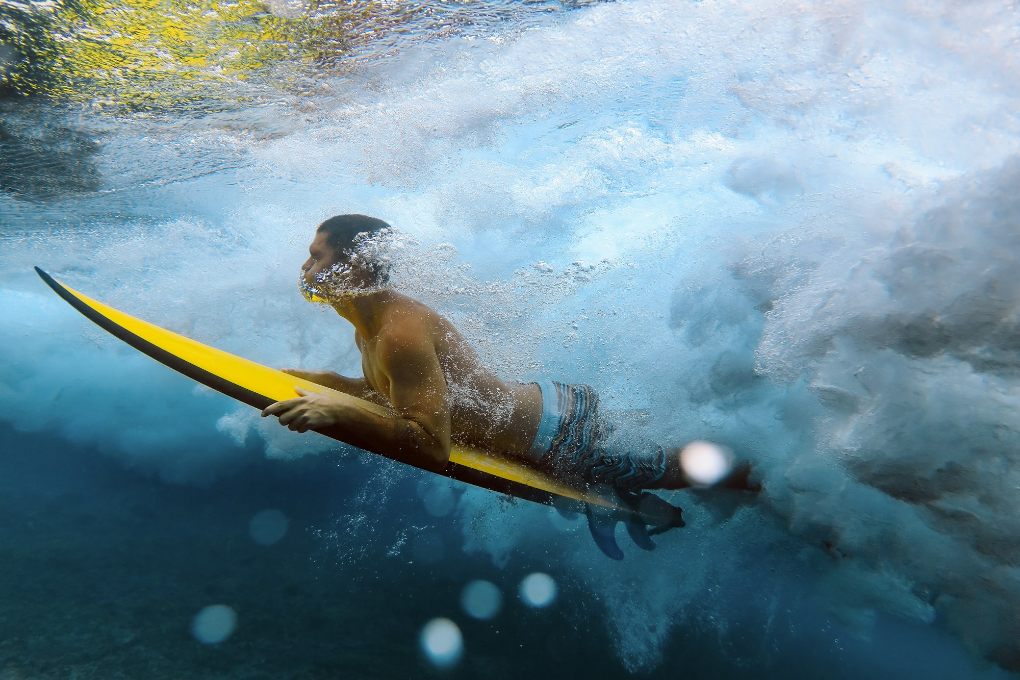 Shirtless male surfer diving in sea at Maldives