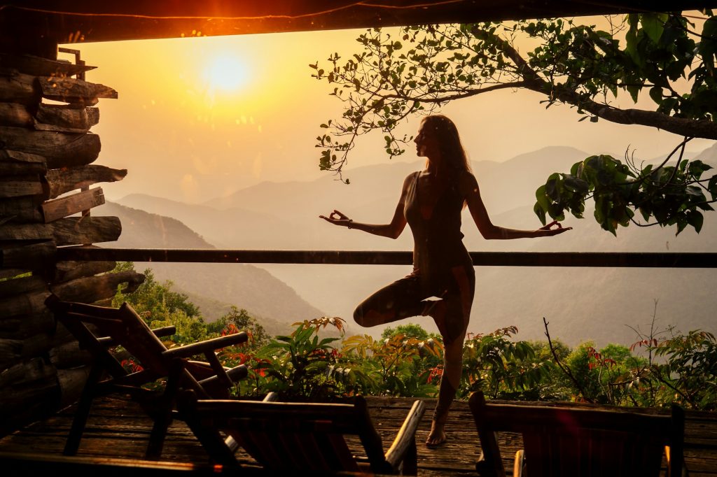 woman in tropical open yoga studio place a view outside to the hills while sunset.