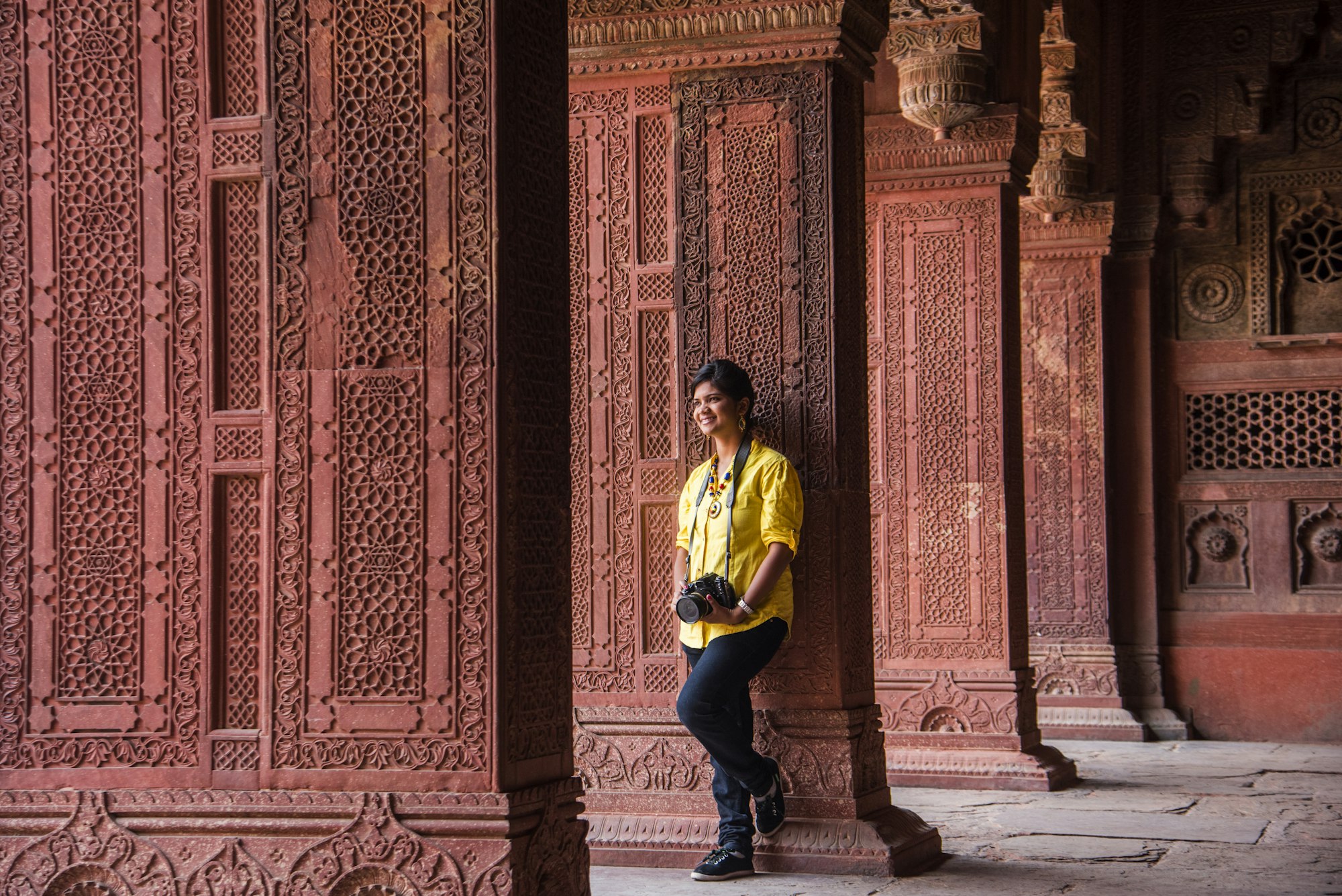 Young woman tourist with camera at Red Fort, Agra, India.